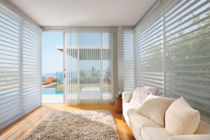 A living room with a sliding glass door and blinds.